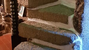 Eine Mauer aus Stein mit einer strukturierten Oberfläche und einer dekorativen Metallspirale.