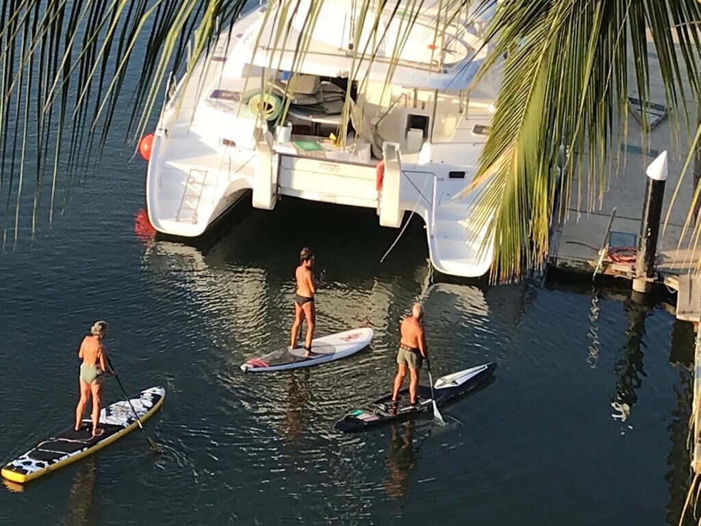 Tres tablas de remo en aguas tranquilas cerca de un barco atracado.