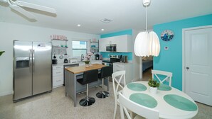 A modern kitchen with a refrigerator, stove, and microwave. There is a dining table with chairs and a ceiling fan. - Clean & Modern, Close to Beach, Restaurants, Downtown SRQ! (Sarasota)