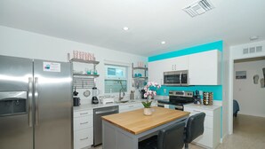 A modern kitchen with stainless steel appliances, a wooden island, and a teal accent wall. - Clean & Modern, Close to Beach, Restaurants, Downtown SRQ! (Sarasota)