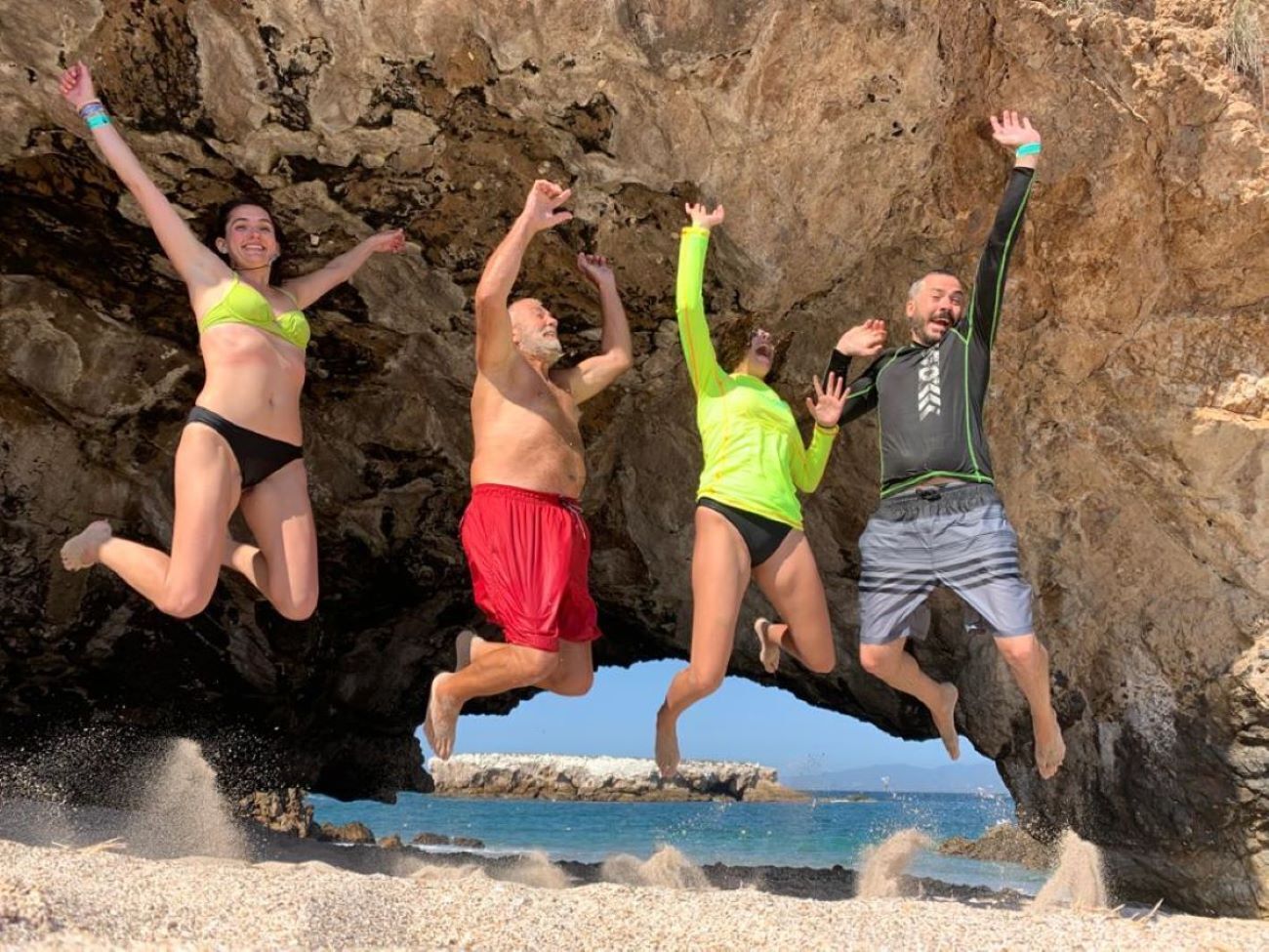A group of people jumping in front of a rocky cliff.