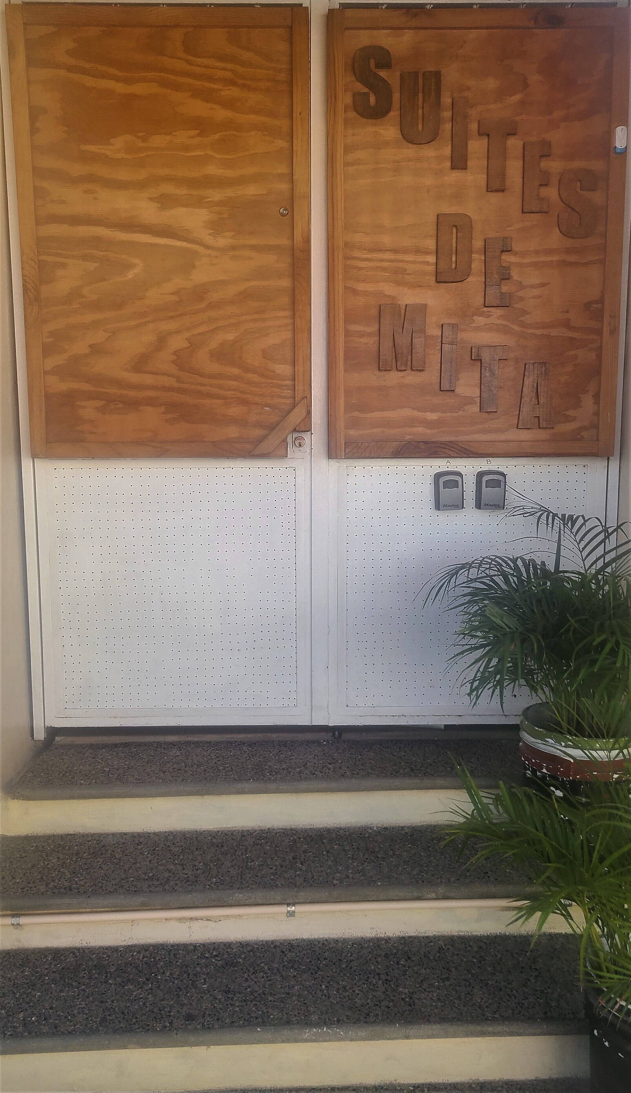 A wooden door with the text "SUITES DE MUTA" and a white panel with a pegboard.