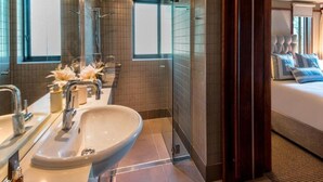 A modern bathroom with a large sink, a shower, and a bed with blue pillows. - Hamilton Island Yacht Club Villas (Whitsundays)