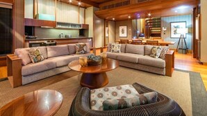 A spacious living area with a large sectional sofa, a round coffee table, and a dining area with a wooden table and chairs. - Hamilton Island Yacht Club Villas (Whitsundays)