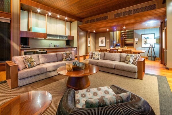 A spacious living area with a large sectional sofa, a round coffee table, and a dining area with a wooden table and chairs.