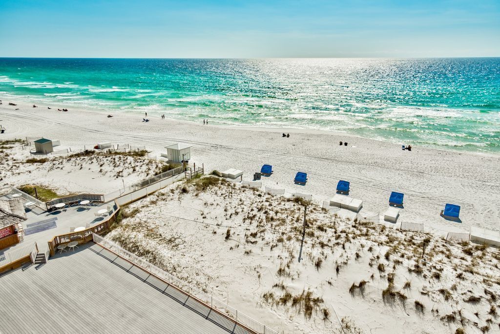 Une plage avec une promenade en bois, des chaises de plage et un poste de surveillance pour les sauveteurs.