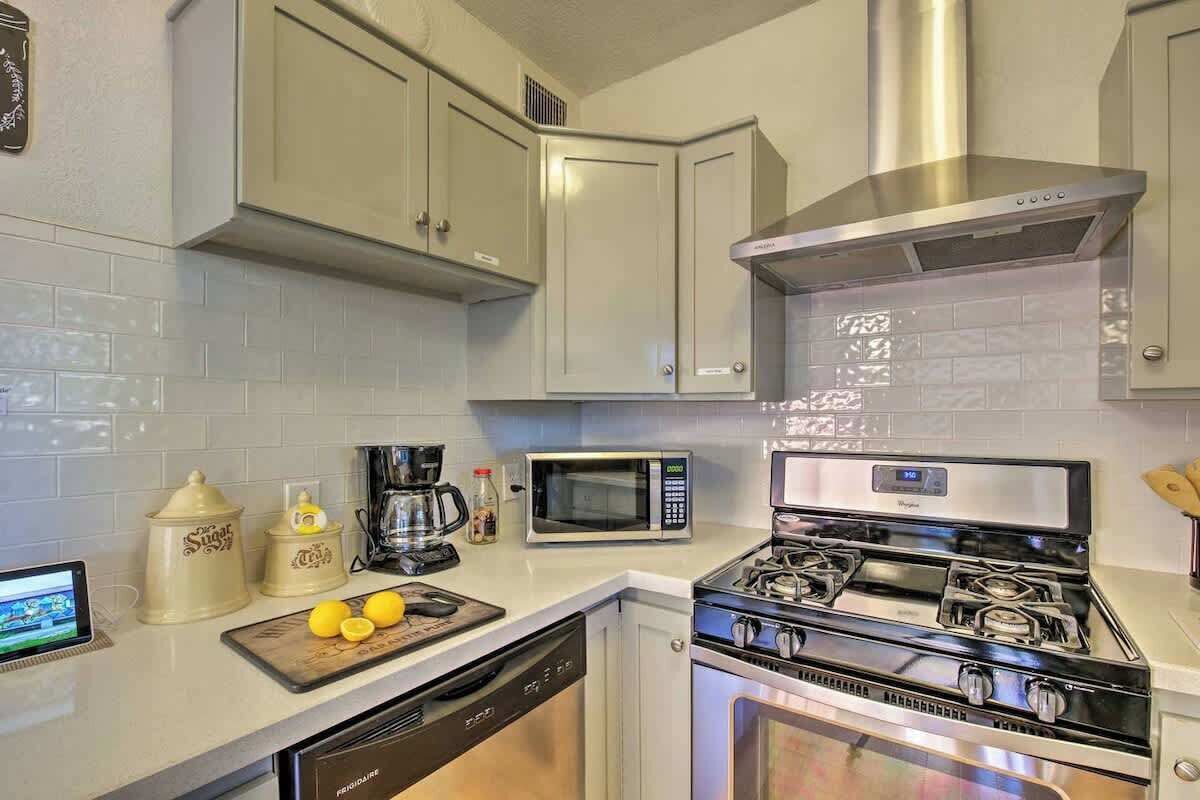 A kitchen with white cabinets, a stainless steel range hood, a microwave, a stove, and a dishwasher.