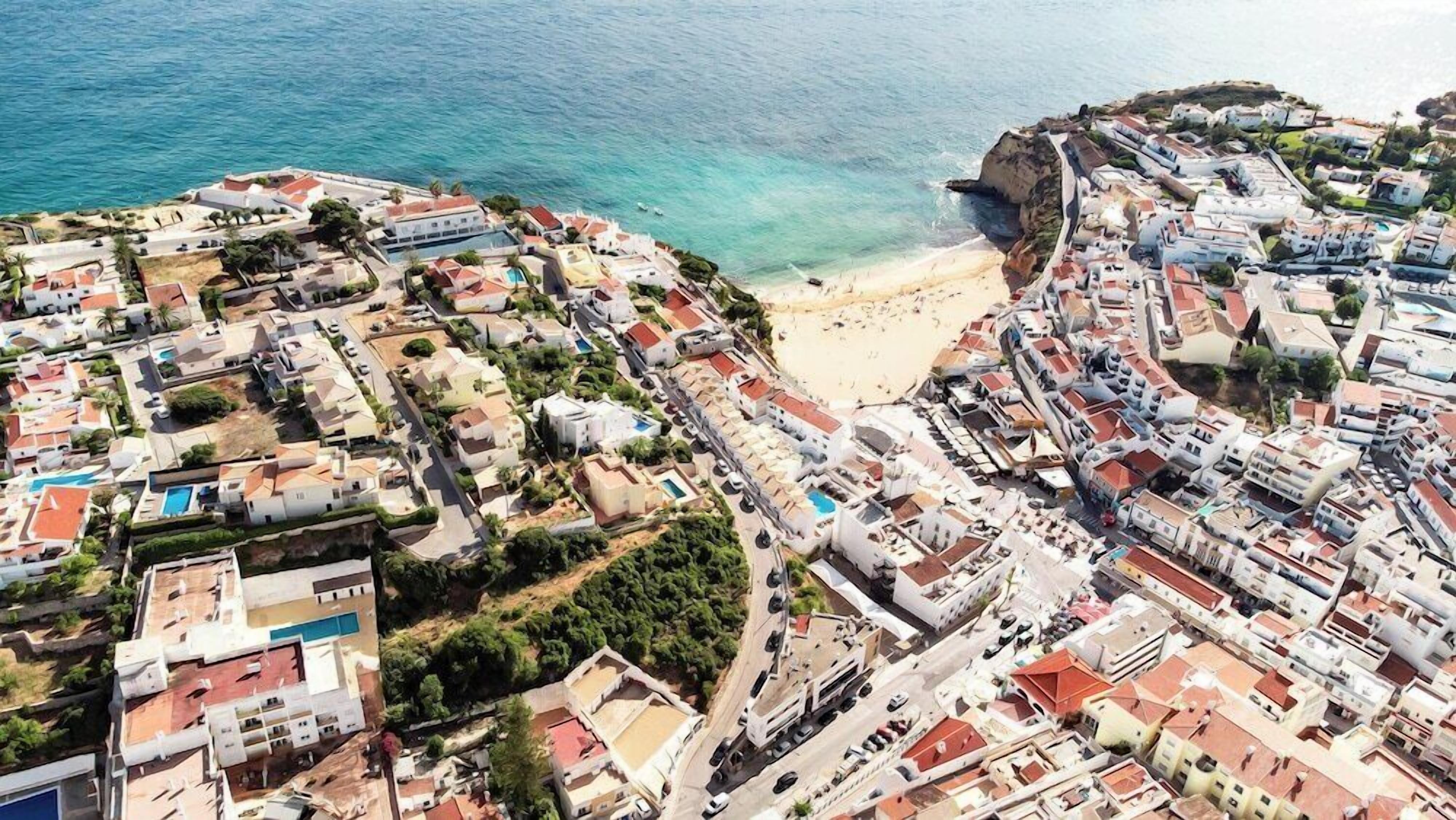 An aerial view of a coastal town with buildings, a beach, and a cliff.