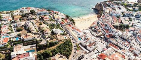 An aerial view of a coastal town with buildings, a beach, and a cliff.