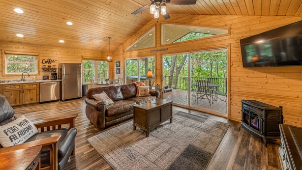 Een gezellig interieur van een chalet met een houten plafond, een open haard, een eethoek en een keuken.