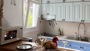 A kitchen with white cabinets, a microwave, a fruit bowl, and a hanging light fixture.