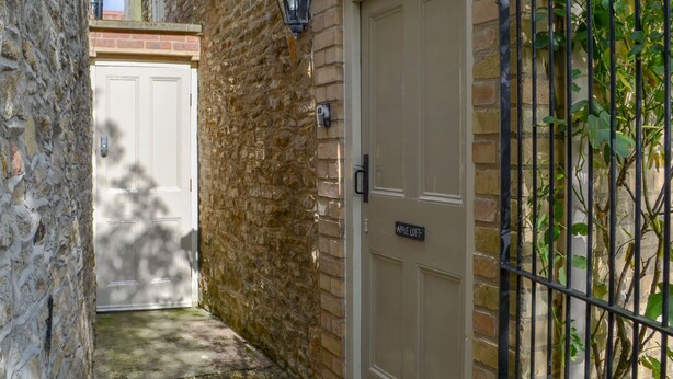 A narrow alleyway with a stone wall, a metal gate, and a beige door labeled "APPLE LOFT". - 1 bedroom accommodation in Nordham, near Beverley (Nordham, near Beverley)