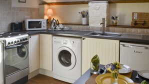 A compact kitchen with a built-in washing machine, a microwave, and a stove. - 1 bedroom accommodation in Nordham, near Beverley (Nordham, near Beverley)