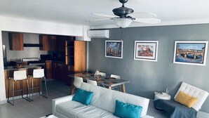 A modern living room with a white sofa, a coffee table, and a dining area with a table and chairs. - Beautiful 2 bedroom unit, free wifi, pool 3 minutes walk from beach  (Punta Cana)