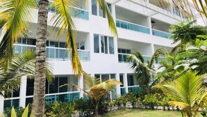 A multi-story building with balconies, surrounded by palm trees and greenery. - Beautiful 2 bedroom unit, free wifi, pool 3 minutes walk from beach  (Punta Cana)
