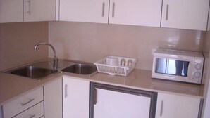A compact kitchen with a sink, a microwave, and a small refrigerator.