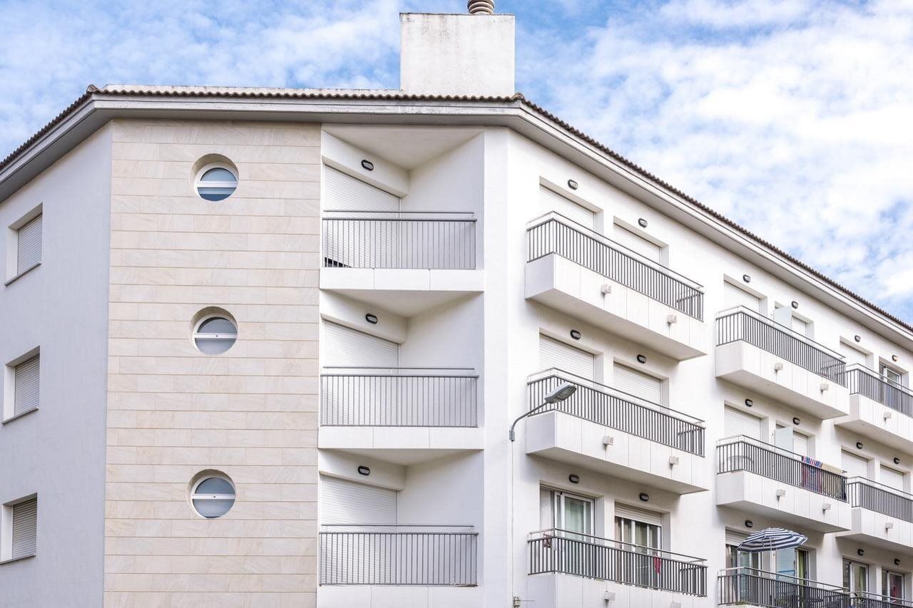 Un edificio moderno de varios pisos con balcones, ventanas y techo plano.