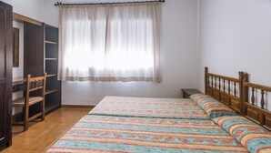 A bedroom with a bed, a wardrobe, a chair, and a window with curtains.