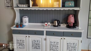 A kitchen with a vintage aesthetic, featuring a white cabinet with drawers, a coffee maker, a kettle, and a retro radio. - Vacation home San Giovanni nei Sassi (Matera)