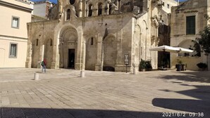 A historic building with a large arched entrance, a bell tower, and a courtyard with a paved ground. - Vacation home San Giovanni nei Sassi (Matera)