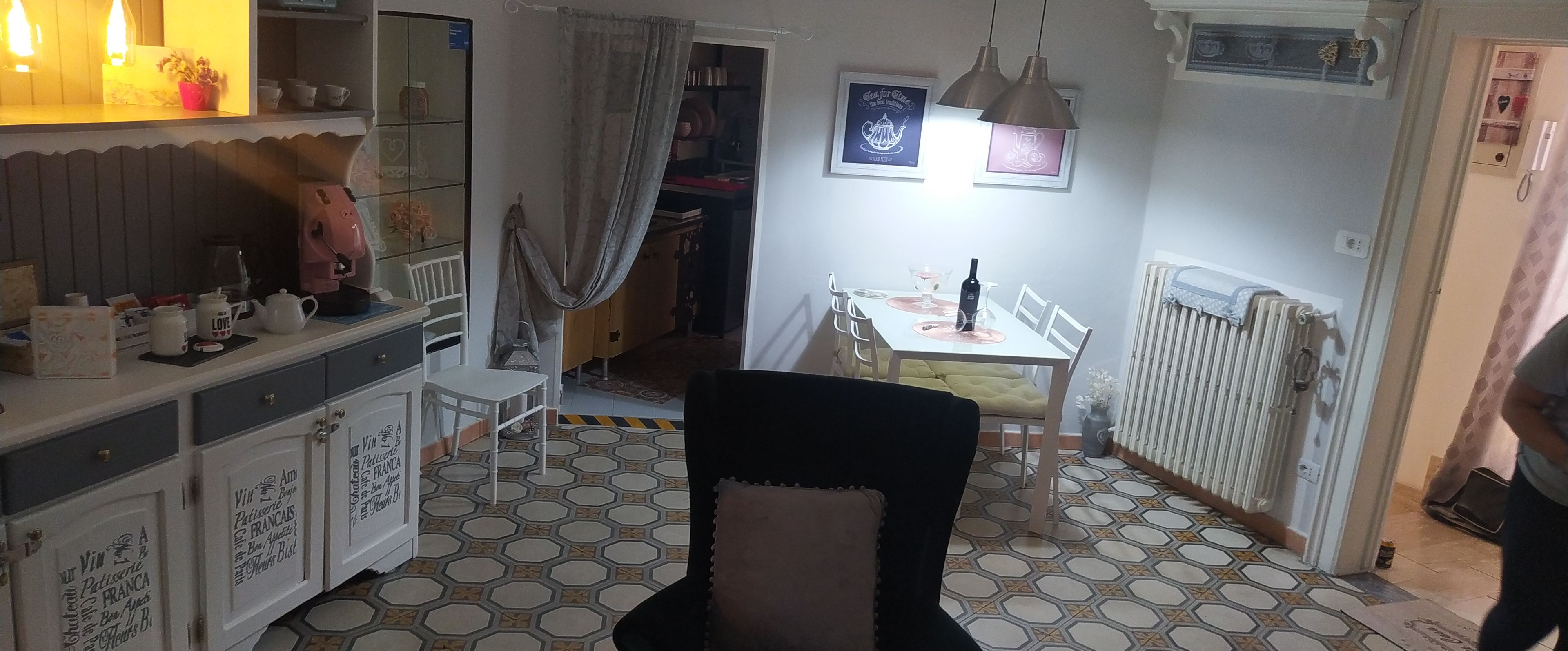 A dining area with a table set for two, a black chair, and a radiator.