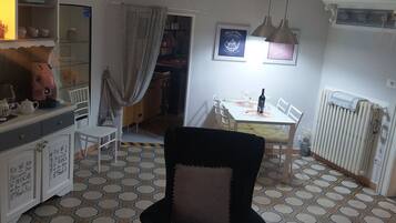 A dining area with a table set for two, a black chair, and a radiator.