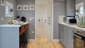 Une cuisine moderne avec des meubles de couleur grise, un plancher en bois et un bar pour prendre le petit-déjeuner, agrémenté de tabourets.