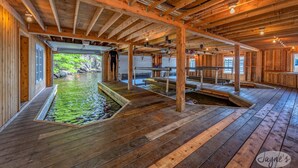 A wooden cabin interior with a large open space, wooden beams, and a small water feature.