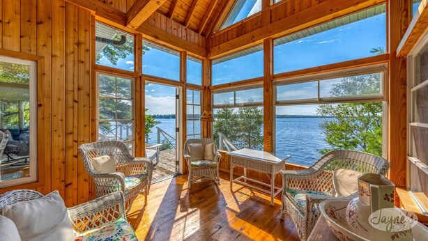 A wooden cabin with large windows overlooking a lake.