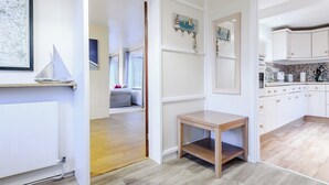 A modern kitchen with white cabinets, a wooden table, and a view into the adjacent bedroom. - 3 bedroom accommodation in Brancaster Staithe, near Wells-next-the-Sea (Brancaster Staithe, near Wells-next-the-Sea)