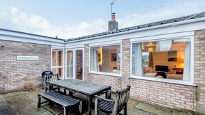 A brick house with a sign reading "MARSDEN ST." and a patio with a wooden table and benches. - 3 bedroom accommodation in Brancaster Staithe, near Wells-next-the-Sea (Brancaster Staithe, near Wells-next-the-Sea)