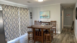 Uma sala de jantar com uma mesa e cadeiras de madeira, um quadro na parede e cortinas estampadas.