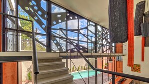 A modern interior with a staircase leading to a balcony overlooking a swimming pool.