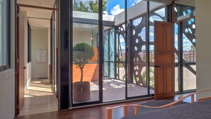 A modern room with a large sliding glass door leading to an outdoor area with a potted tree and a view of the sky.