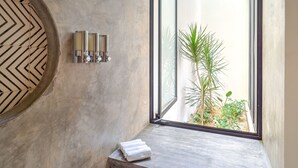 A modern bathroom with a large window, a towel rack, and a decorative wall panel.