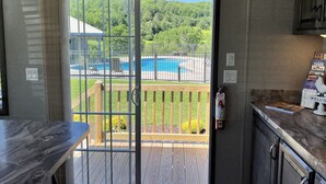 A kitchen with a view of a pool and deck, a fire extinguisher, and a welcome sign. - Coop Diamonds - Honey Joe Acres, sleeps 4, Private heated pool (Fly Creek)