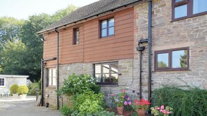 A stone building with a wooden facade, multiple windows, and a paved entrance.
