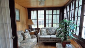 A cozy room with wicker furniture, a large window, and a potted plant.