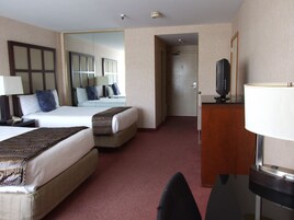 Una habitación de hotel con dos camas, un escritorio con lámpara, televisión y espejo.