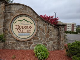 Un muro de piedra con un letrero circular para Hudson Valley Resort & Spa.