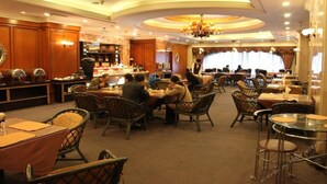A restaurant with wooden paneling, round tables, wicker chairs, and a chandelier. - International Hotel (Jiaxing)