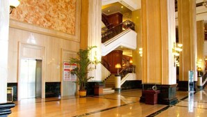 A spacious lobby with marble flooring, a staircase, and a large potted plant. - International Hotel (Jiaxing)