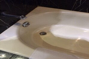 A bathtub with a faucet and a drain.