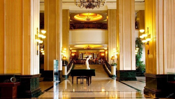 A grand lobby with high ceilings, a central staircase, and a piano. - International Hotel (Jiaxing)