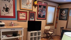 A living room with a TV, framed posters, a white entertainment unit, and a dining area. - End Unit;walk to lifts,or take free bus winter; Ski History Exhibit (Mount Crested Butte)