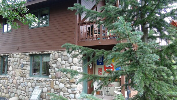 A stone building with a wooden balcony, a sign indicating ski tips, and a closed sign. - End Unit;walk to lifts,or take free bus winter; Ski History Exhibit (Mount Crested Butte)