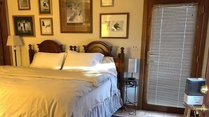 A bedroom with a bed, a bedside table, a lamp, a door with blinds, and a wall with framed pictures. - End Unit;walk to lifts,or take free bus winter; Ski History Exhibit (Mount Crested Butte)