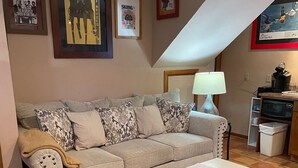A living room with a sofa, a coffee table, a lamp, and a kitchen area with a microwave. - End Unit;walk to lifts,or take free bus winter; Ski History Exhibit (Mount Crested Butte)