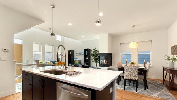 A modern kitchen with a large island, built-in appliances, and a dining area with a table and chairs. - Remarkable home near Old Town, Breweries, & River! (Fort Collins)