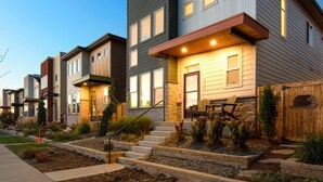 A row of modern townhouses with a stone facade, wooden deck, and outdoor seating area. - Remarkable home near Old Town, Breweries, & River! (Fort Collins)